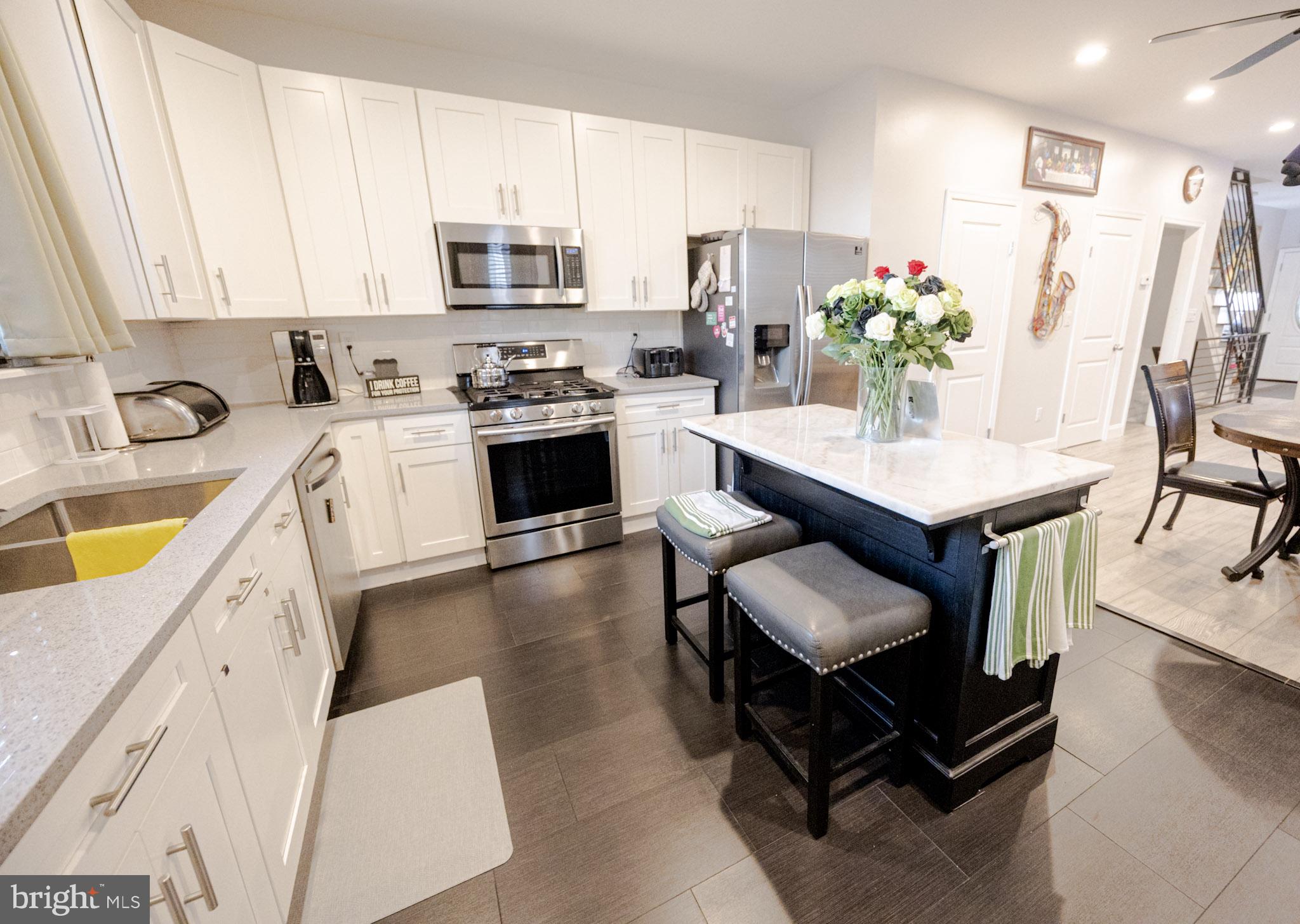 6113 Ross Street Philadelphia, PA 19144 - Photo 17 of 40 a kitchen with stainless steel appliances kitchen island granite countertop a table chairs microwave and sink
