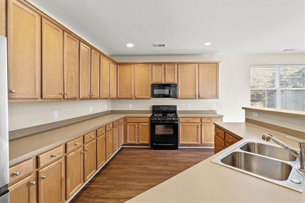 125 Parkmont Court Dallas, GA 30132 - Photo 17 of 36 a kitchen with granite countertop a sink dishwasher stove and cabinets with wooden floor