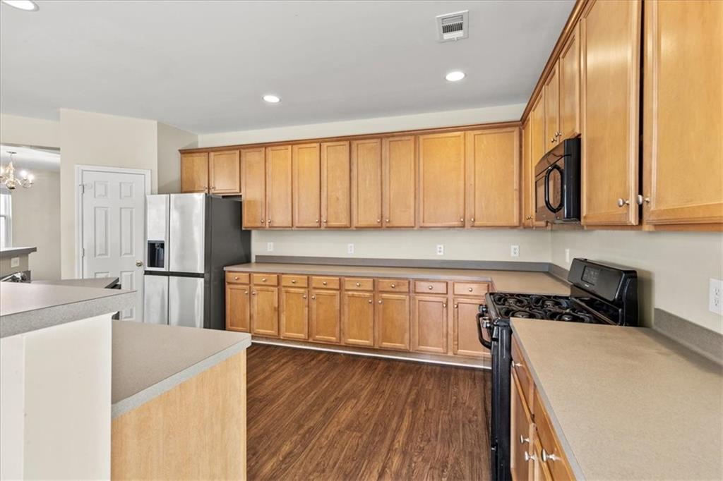 125 Parkmont Court Dallas, GA 30132 - Photo 19 of 36 a kitchen with stainless steel appliances granite countertop a refrigerator a sink dishwasher and wooden cabinets with wooden floor