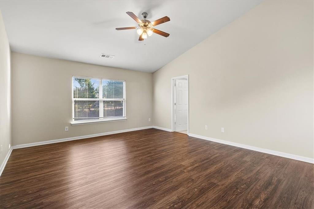 125 Parkmont Court Dallas, GA 30132 - Photo 24 of 36 an empty room with wooden floor chandelier fan and windows