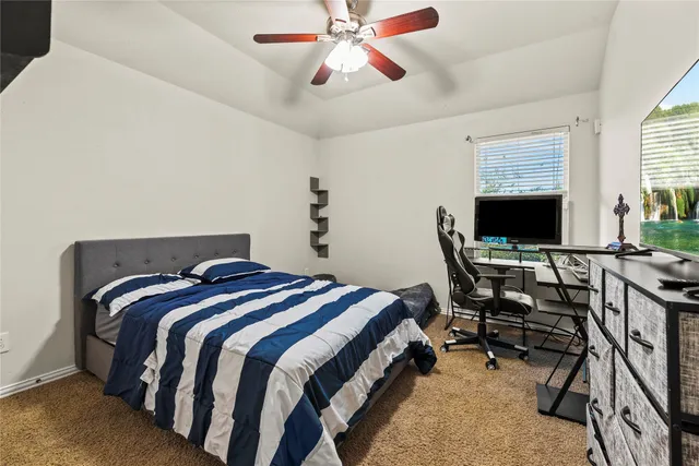 a bedroom with a bed a computer on the desk and chair