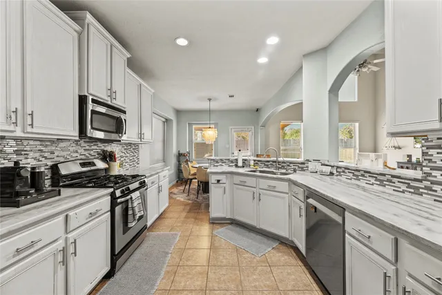 a kitchen with stainless steel appliances granite countertop a stove top oven a sink dishwasher and a refrigerator