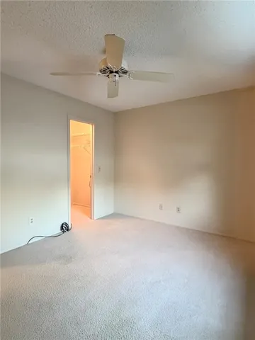 an empty room with a chandelier fan and windows