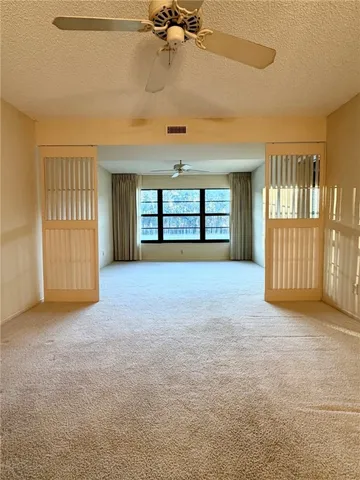 an empty room with windows and ceiling fan