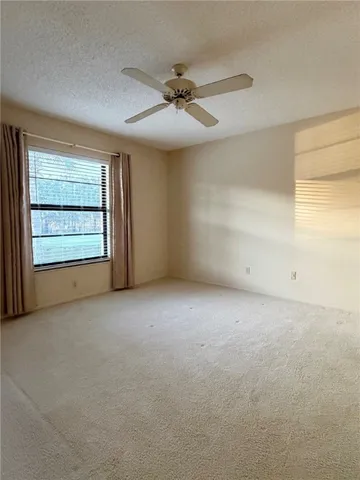 an empty room with a ceiling fan and window