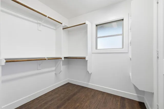 an empty room with wooden floor ceiling fan and windows