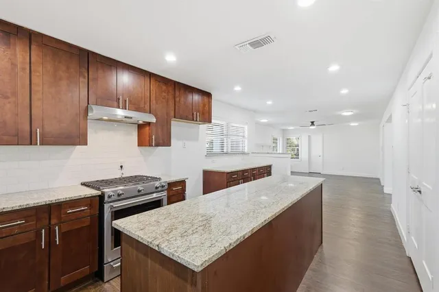 a kitchen with stainless steel appliances granite countertop wooden cabinets sink and stove