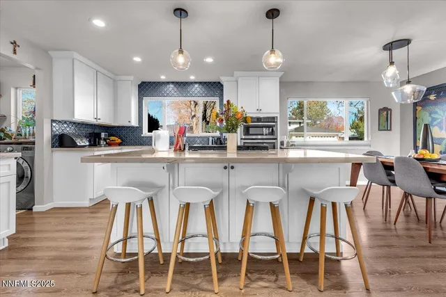 a kitchen with stainless steel appliances kitchen island granite countertop a dining table chairs and white cabinets