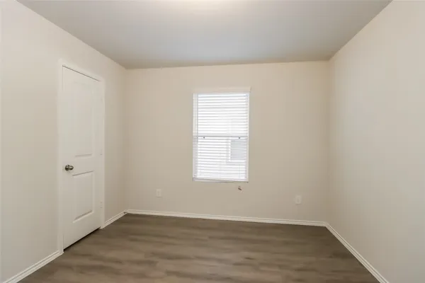 an empty room with wooden floor and window