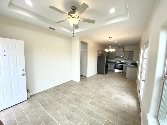 a view of an empty room and kitchen view