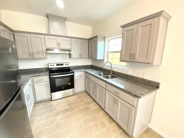 a kitchen with stainless steel appliances granite countertop a sink stove and cabinets