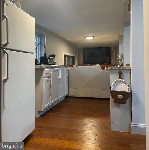 a living room with stainless steel appliances furniture a refrigerator and a dresser