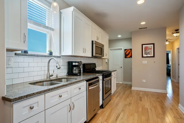 a kitchen with granite countertop a sink cabinets and stainless steel appliances
