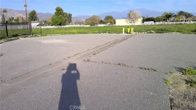 a view of a road with a big yard and large trees