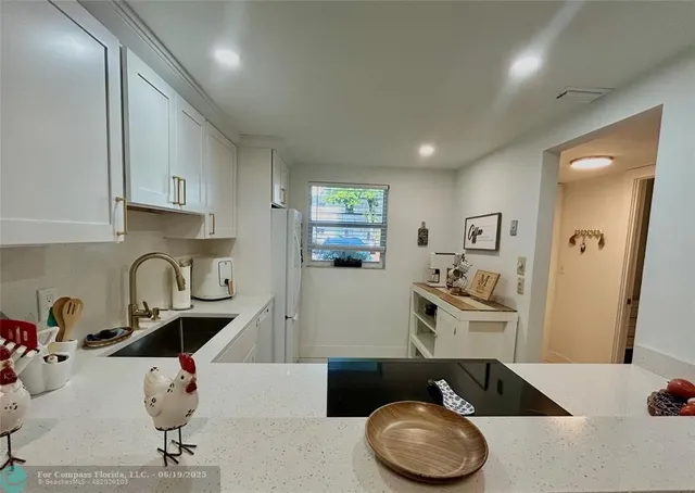 a kitchen with a sink a stove and white cabinets with wooden floor