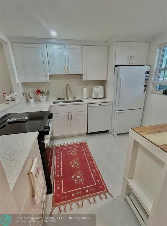 3060 Holiday Springs Boulevard, Unit 102 Margate, FL 33063 - Photo 8 of 12 a kitchen with a refrigerator sink and cabinets