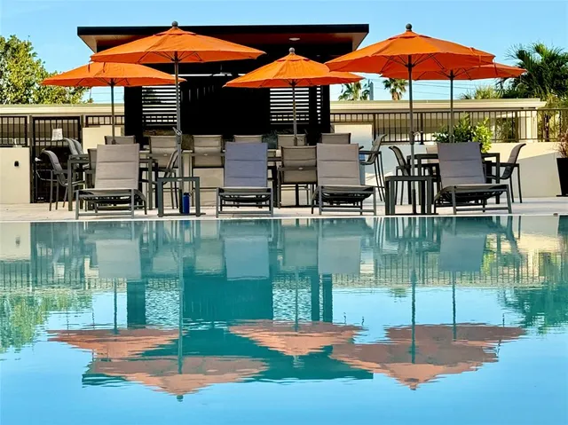 a patio with water view fountain pool table and chairs under an umbrella