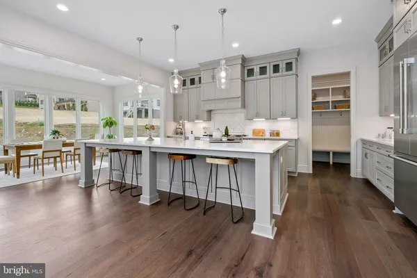 a open kitchen with stainless steel appliances granite countertop a stove a refrigerator a sink dishwasher and a dining table with wooden floor