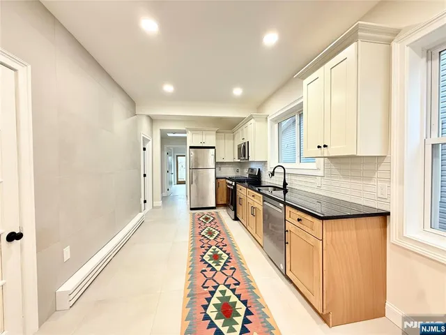 a large kitchen with stainless steel appliances granite countertop a refrigerator and a sink