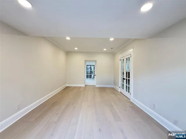 a kitchen with stainless steel appliances granite countertop a stove a sink dishwasher a refrigerator and white cabinets with wooden floor