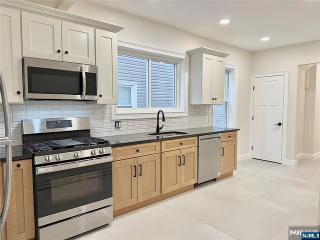 a kitchen with stainless steel appliances granite countertop grey cabinets a stove a sink and dishwasher