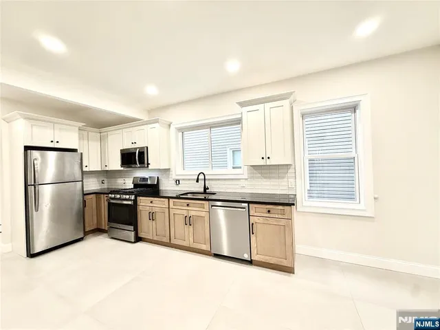 a kitchen with stainless steel appliances granite countertop grey cabinets a stove a sink and dishwasher