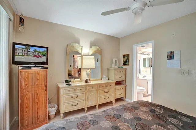 a spacious bedroom with a bed and a flat tv screen on dresser