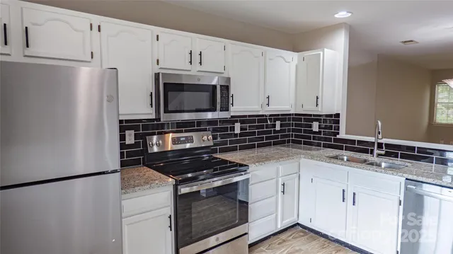 a kitchen with granite countertop white cabinets and stainless steel appliances
