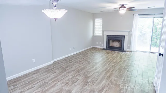 a view of an empty room with a chandelier fan and wooden floor