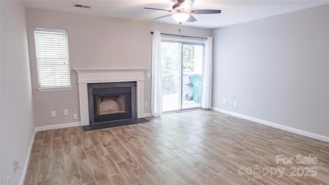 an empty room with wooden floor fireplace and windows