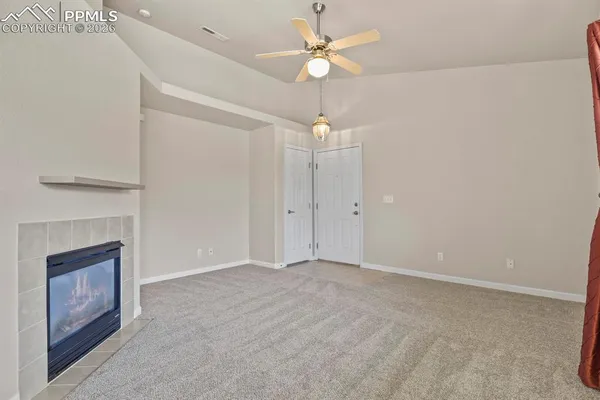 an empty room with fan and fireplace