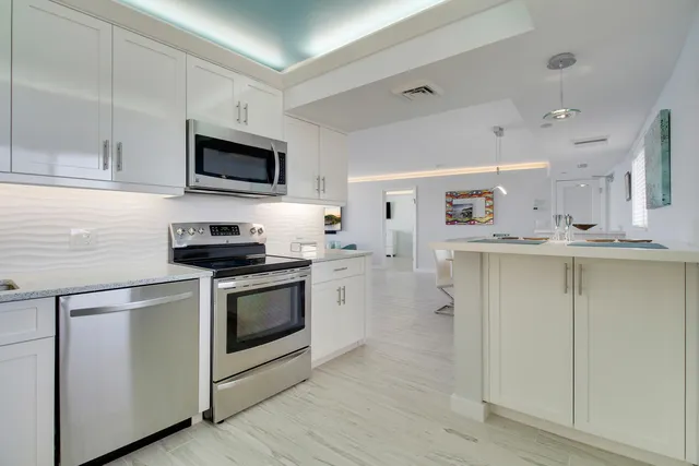 a kitchen with stainless steel appliances granite countertop a stove a sink and a microwave