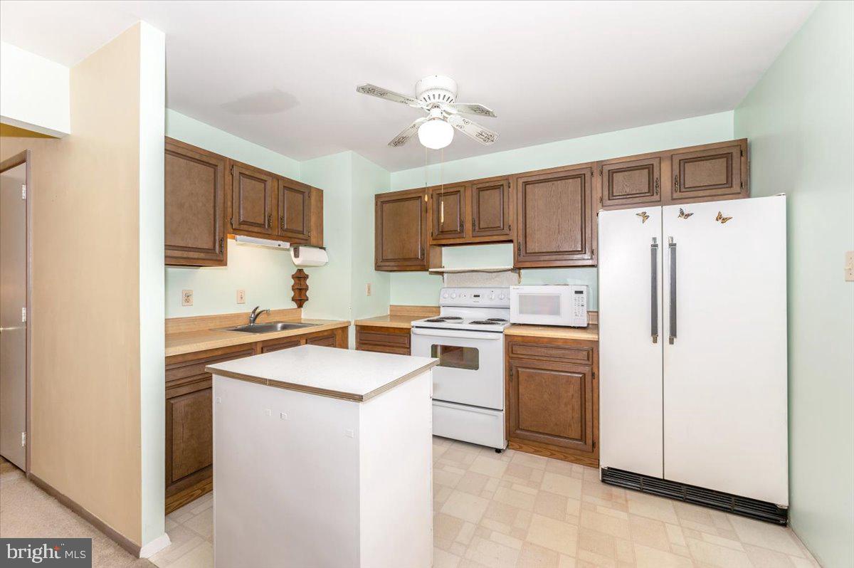 52 Wenner Drive Brunswick, MD 21716 - Photo 21 of 55 a kitchen with a refrigerator a stove top oven a sink dishwasher and white cabinets with wooden floor
