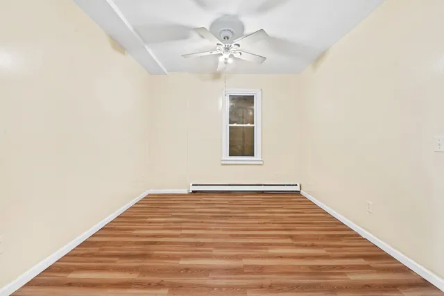 a view of an empty room with chandelier fan and wooden floor