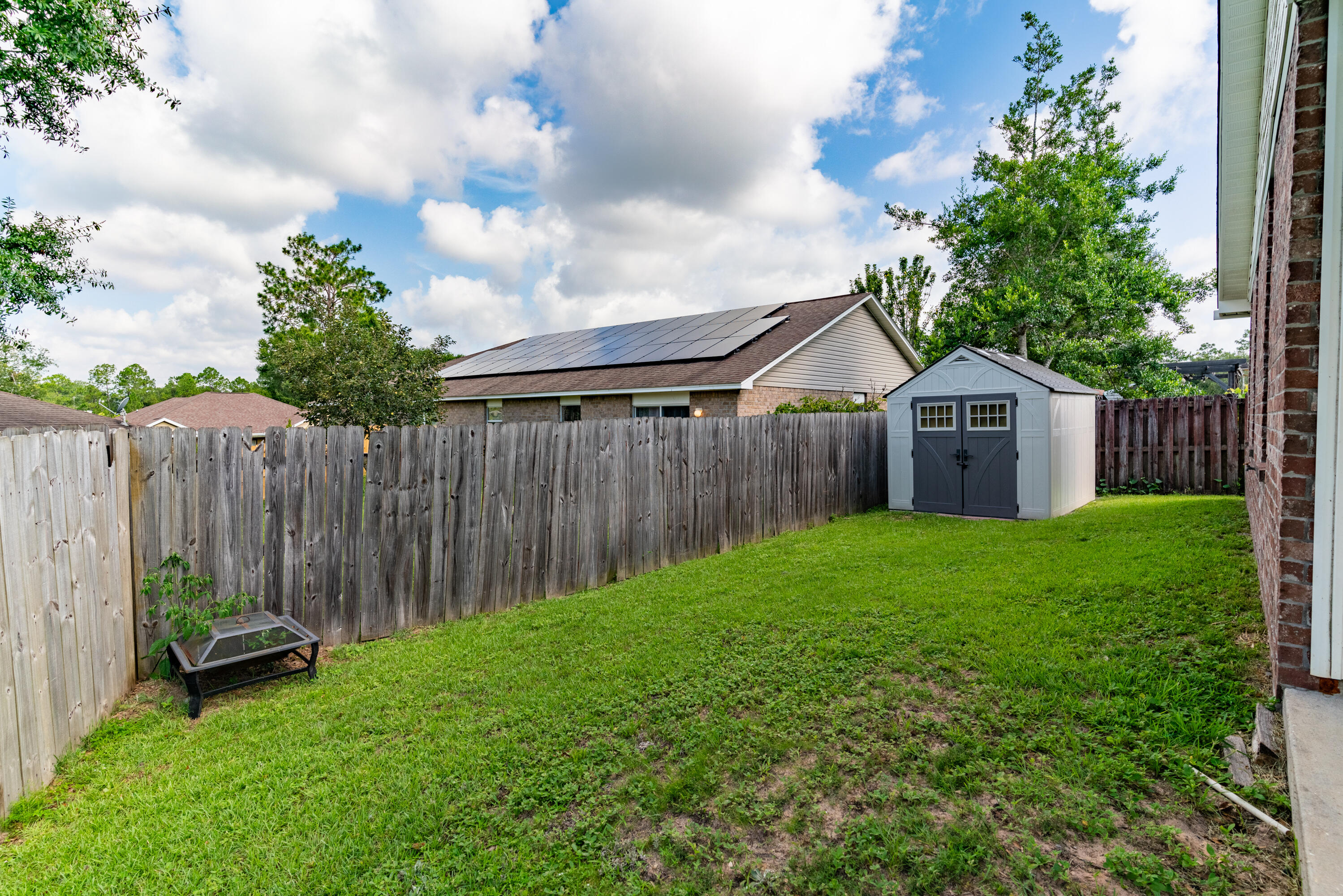 4633 Hermosa Road Crestview, FL 32539 - Photo 44 of 53 a view of a backyard with a small cabin and a chair