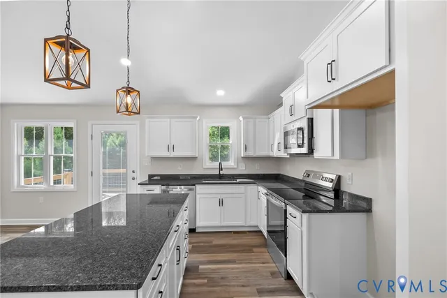 a kitchen with granite countertop a sink a counter space appliances and cabinets