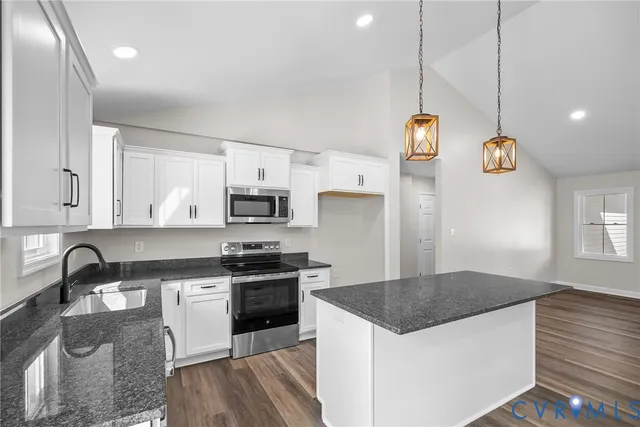 a kitchen with stainless steel appliances granite countertop a sink a stove and a refrigerator