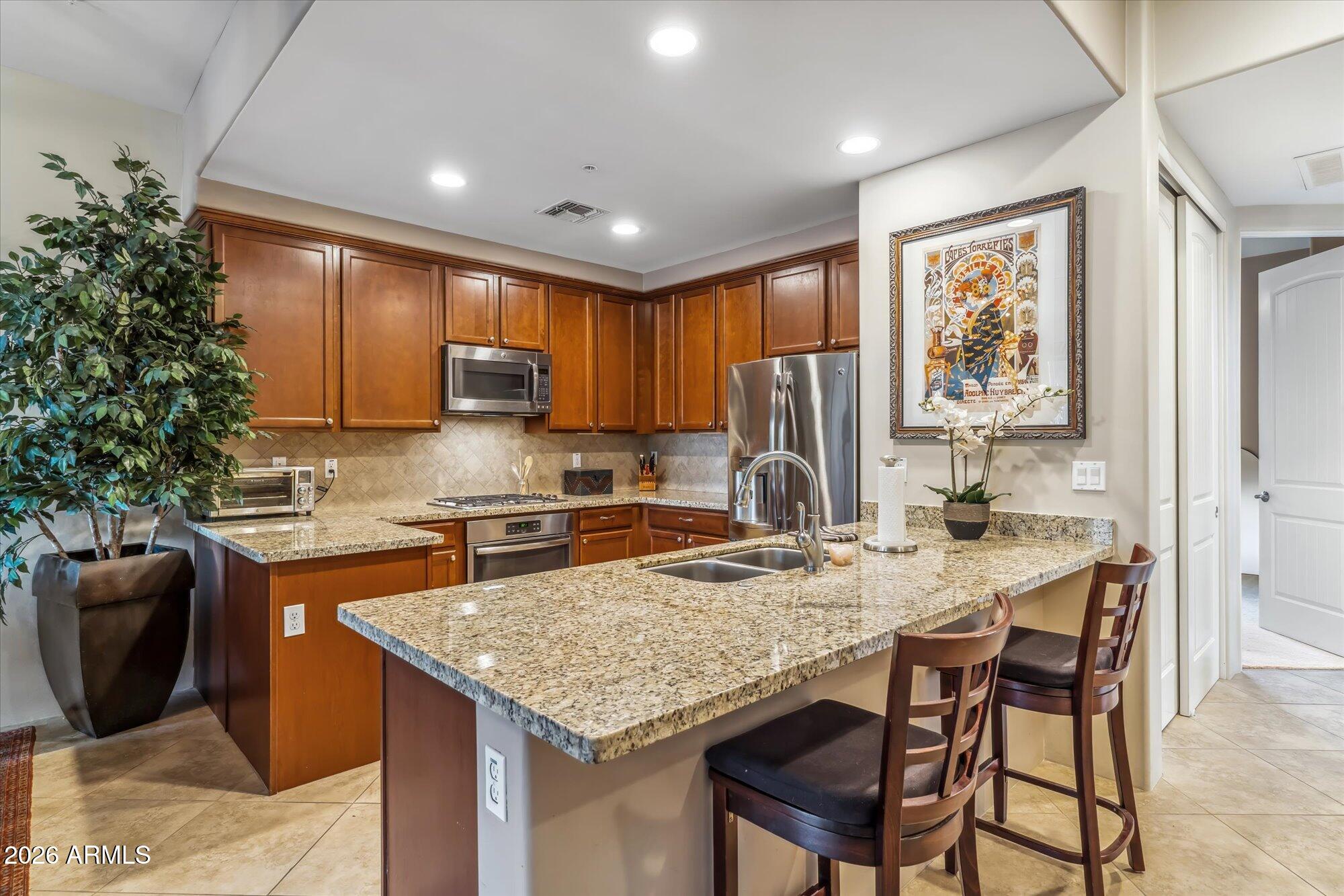 36600 North Cave Creek Road, Unit D11 Cave Creek, AZ 85331 - Photo 10 of 28 a kitchen with granite countertop kitchen island stainless steel appliances a stove refrigerator sink and cabinets