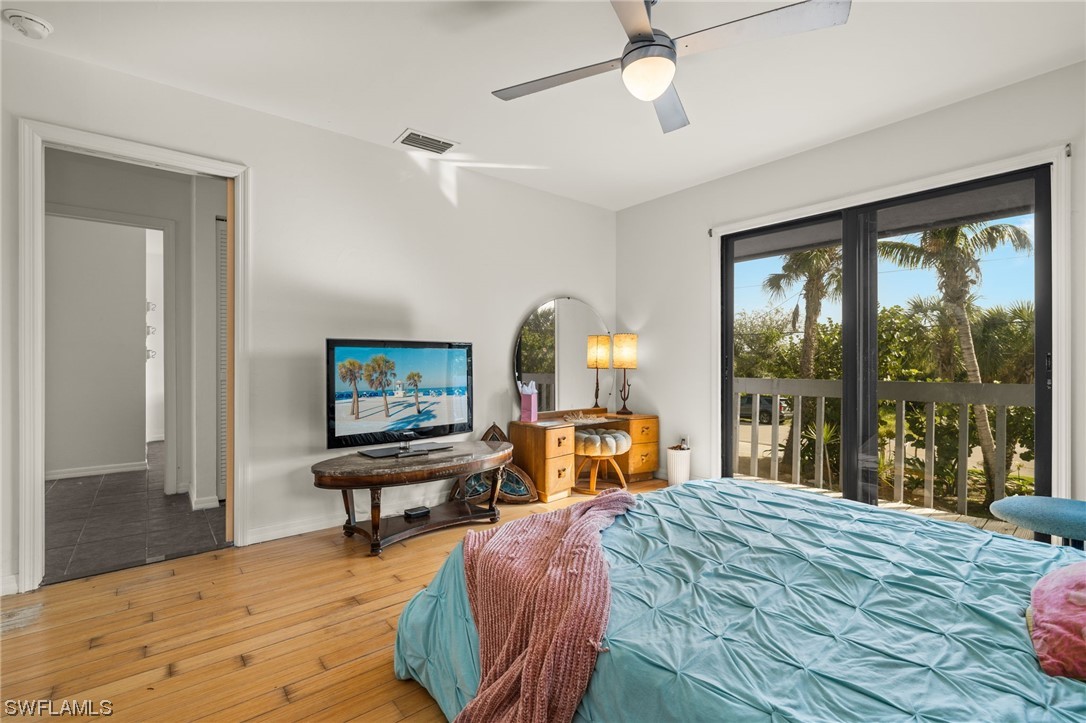 771 Rabbit Road Sanibel, FL 33957 - Photo 16 of 39 a bedroom with a bed a large window and wooden floor