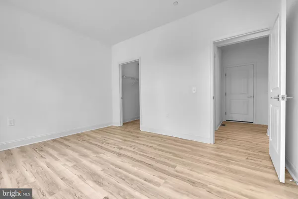 a view of an empty room with wooden floor and closet