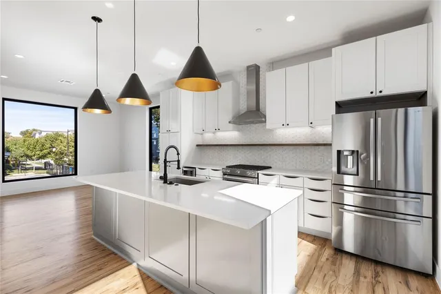 a kitchen with stainless steel appliances a sink a stove a refrigerator and cabinets