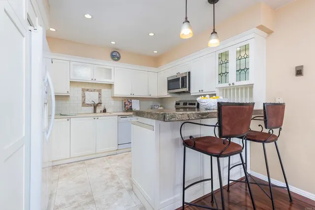 a kitchen with a dining table chairs refrigerator and microwave
