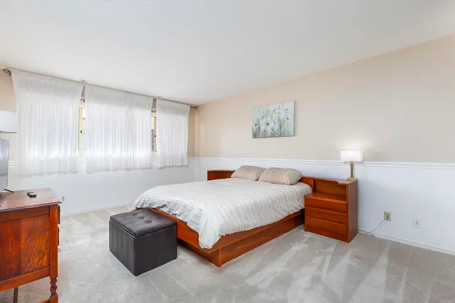 a bedroom with a bed and a lamp on dresser