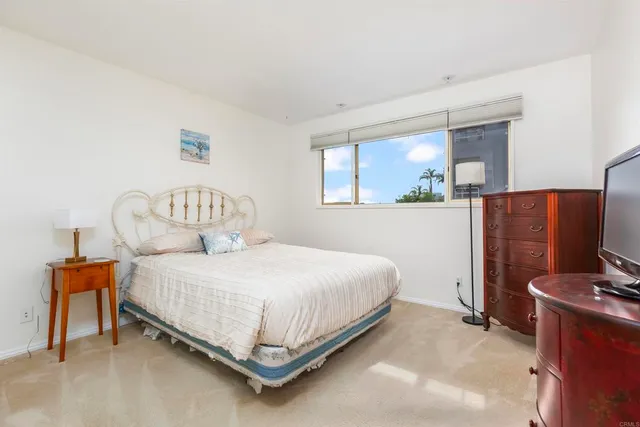 a bedroom with a bed and a flat tv screen on dresser