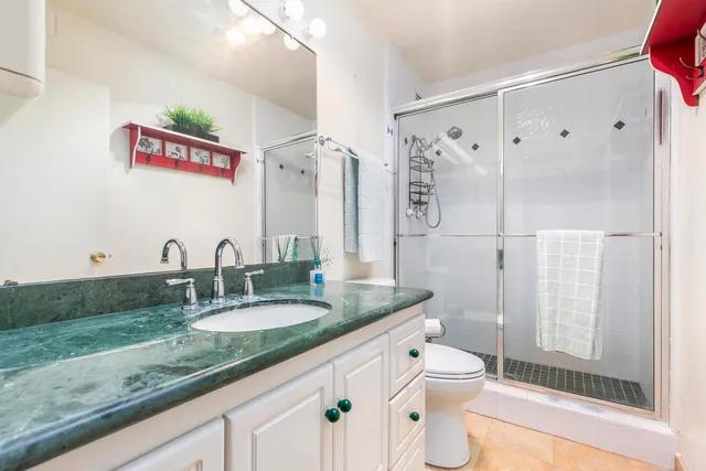 a bathroom with a granite countertop sink mirror vanity and toilet