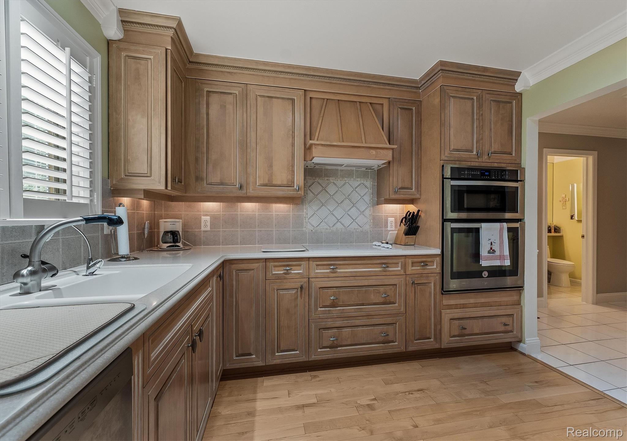 1662 Sumac Drive Rochester, MI 48309 - Photo 15 of 38 Kitchen featuring light wood-finish cabinetry, a white countertop, and a tile backsplash