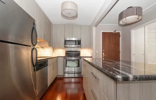a kitchen with kitchen island granite countertop stainless steel appliances a stove refrigerator and cabinets