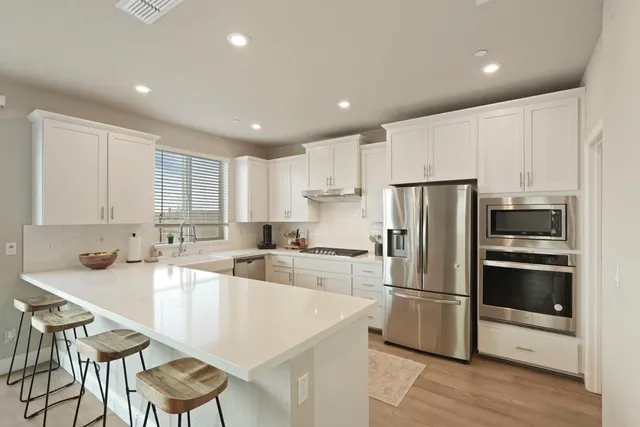 a kitchen with a refrigerator a sink and a stove top oven with wooden floor