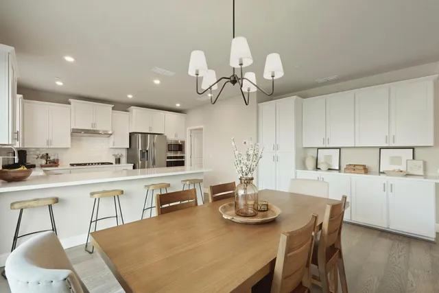 a kitchen with stainless steel appliances granite countertop a sink a stove a dining table and chairs