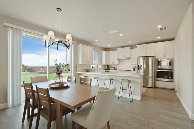 a open dining room with stainless steel appliances kitchen island granite countertop a dining table chairs and white cabinets